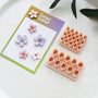 Two cherry blossom petal cutter plates beside small and large clay flowers